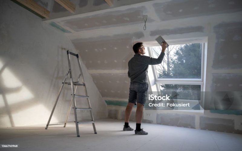 Man plastering drywall in a private house.